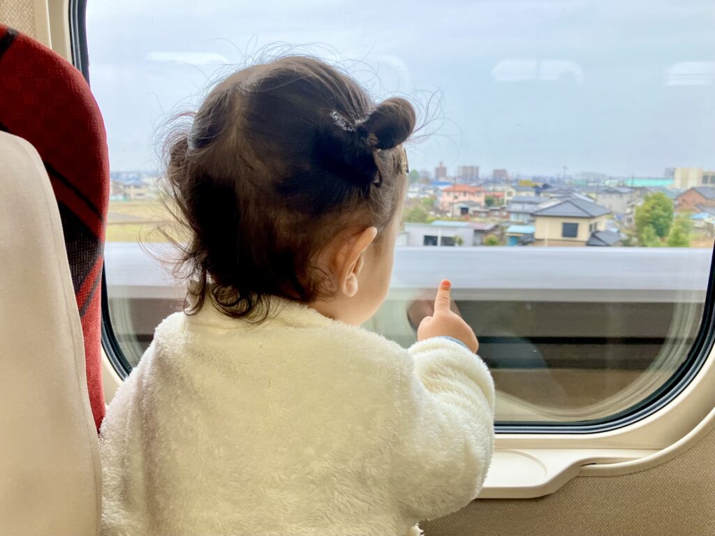 新幹線の窓から外を見る子ども
